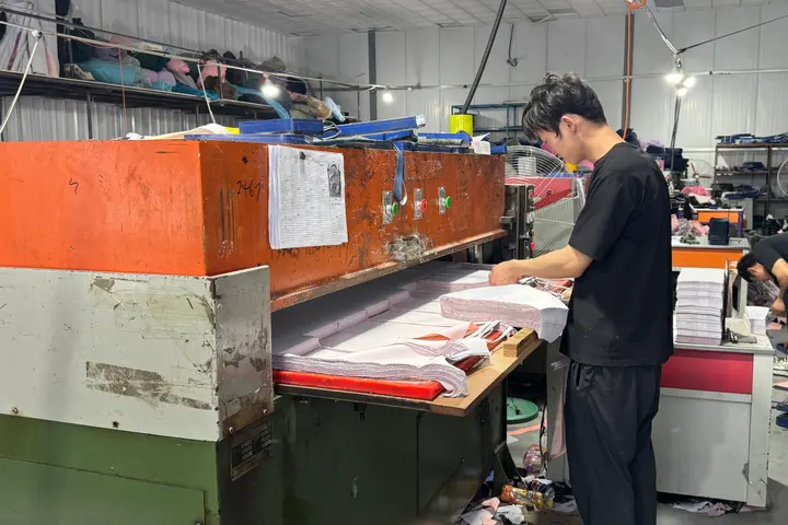Two operators die-cutting bag components on hydraulic presses