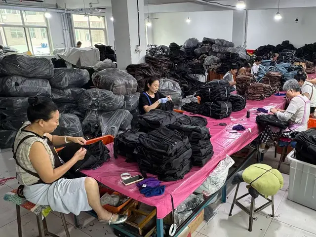 Quality inspectors checking a batch of black backpacks
