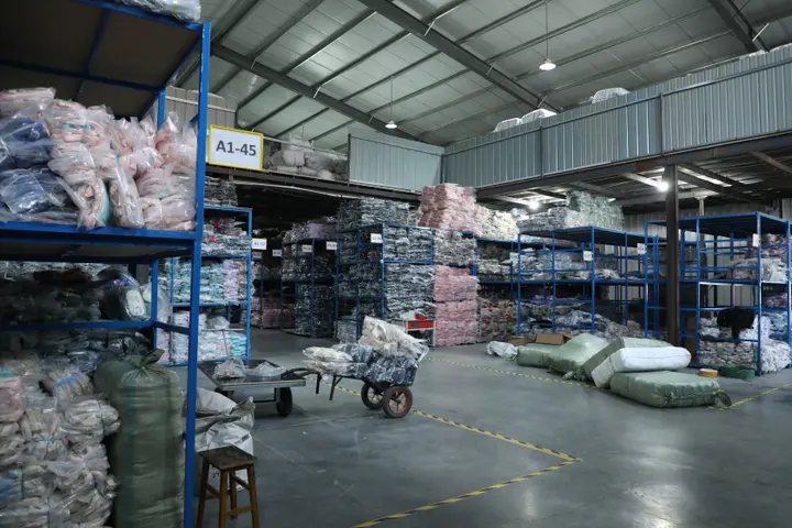 Poly-bagged stock backpacks on racking sorted by style and colour